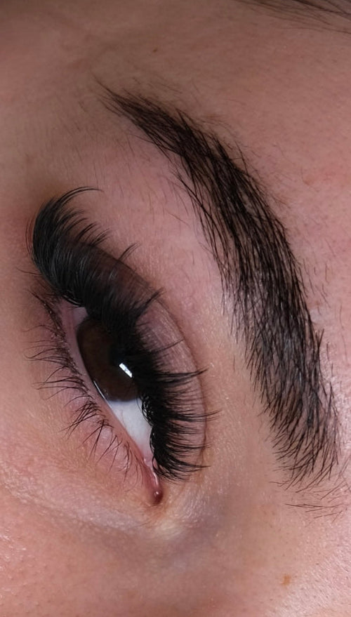 Close-up of a person's eye with long, dark eyelashes.