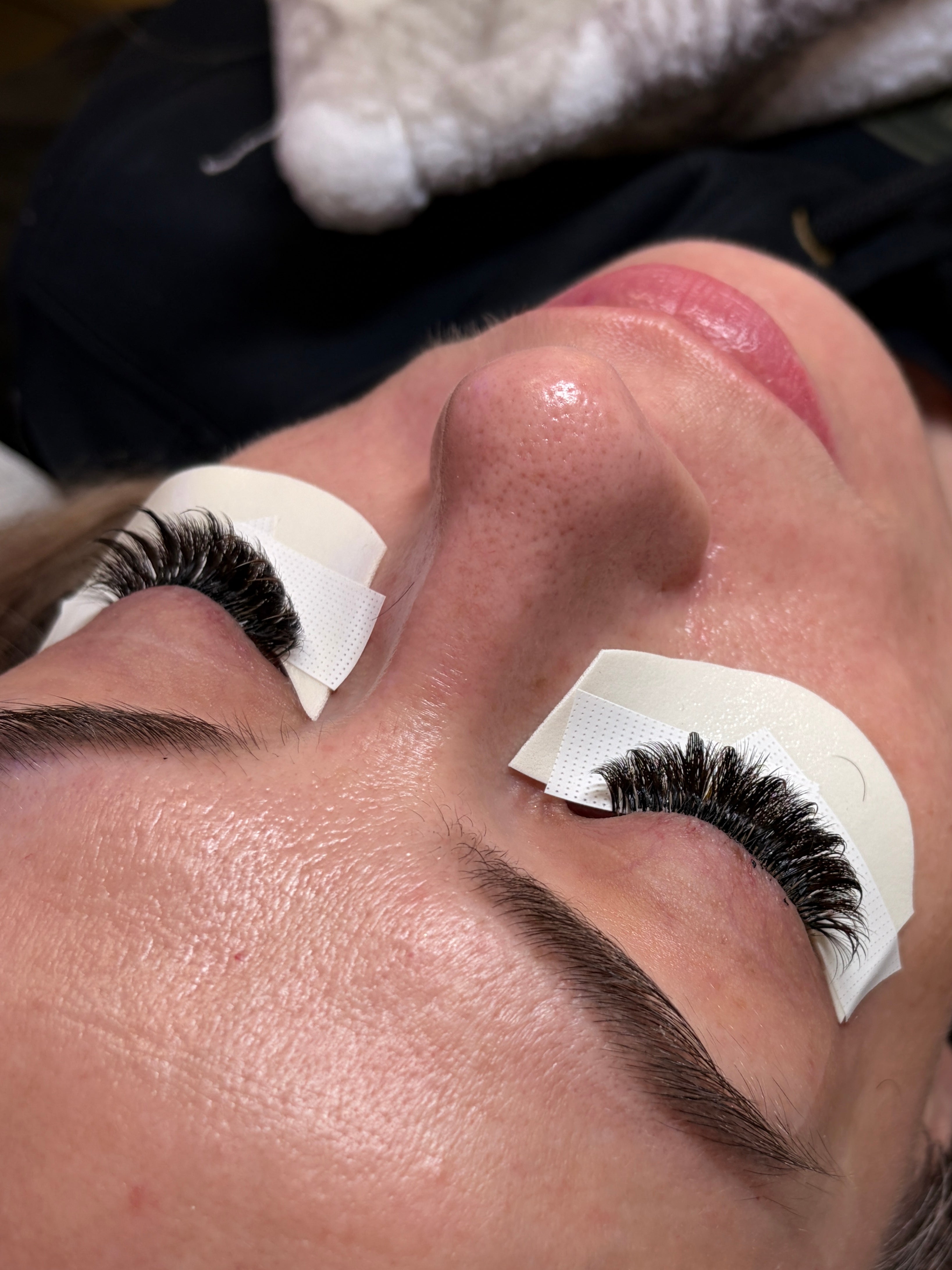 Close-up of a person's eye with false eyelashes being applied.